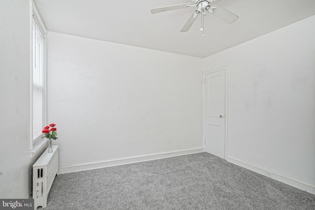 carpeted empty room featuring plenty of natural light, radiator heating unit, and ceiling fan