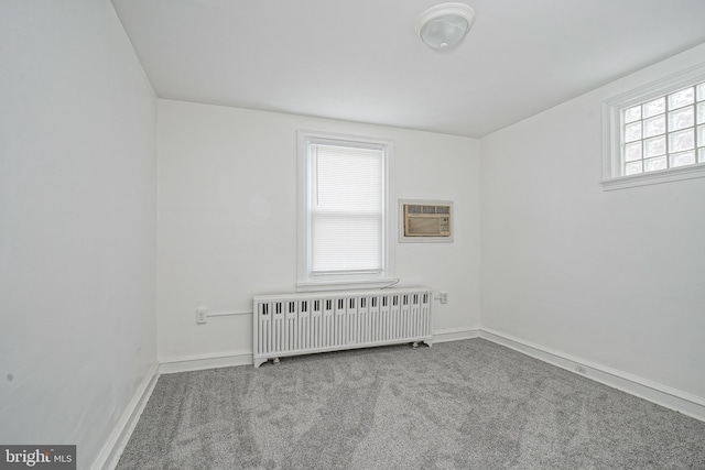 carpeted spare room with radiator heating unit and an AC wall unit