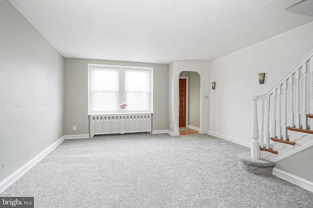 unfurnished living room with radiator and carpet