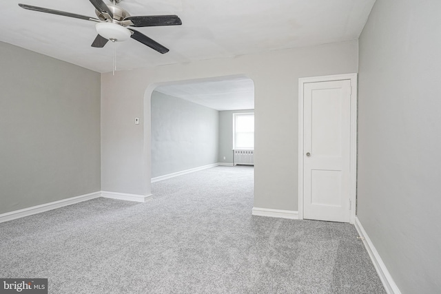 unfurnished room with radiator heating unit, ceiling fan, and carpet