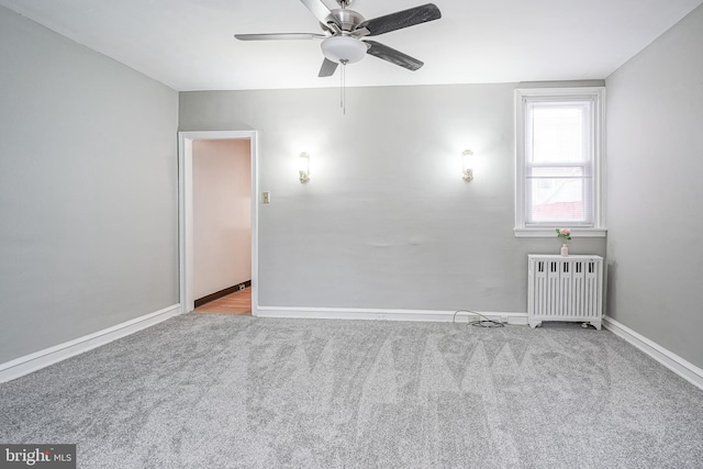 spare room with light carpet, radiator heating unit, and ceiling fan