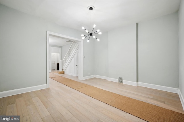 spare room with wood-type flooring and a chandelier