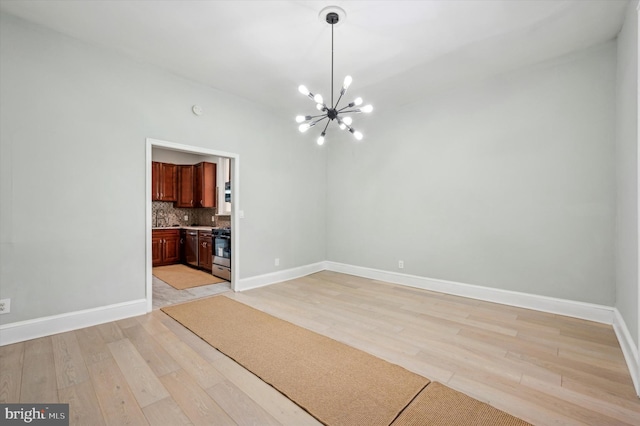 empty room with a notable chandelier and light hardwood / wood-style floors