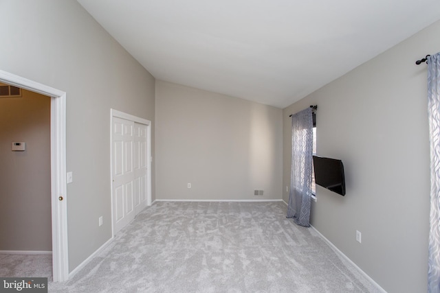 unfurnished living room with lofted ceiling and light colored carpet