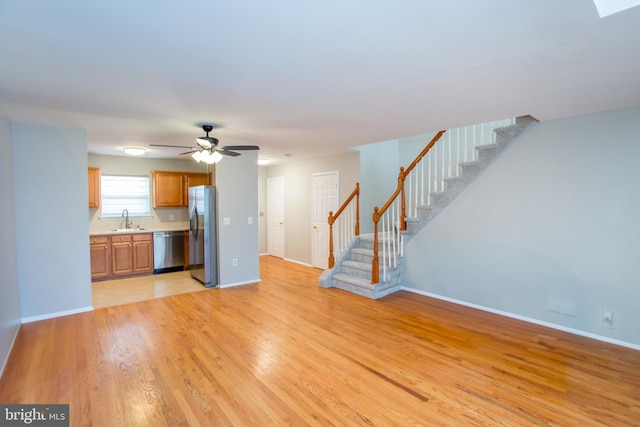 unfurnished living room with ceiling fan, sink, and light hardwood / wood-style floors