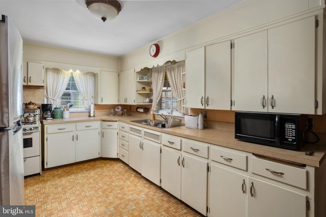 kitchen with sink, stainless steel fridge, white cabinets, and white gas range