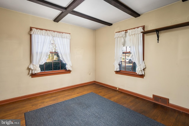 unfurnished room with dark wood-type flooring and beam ceiling