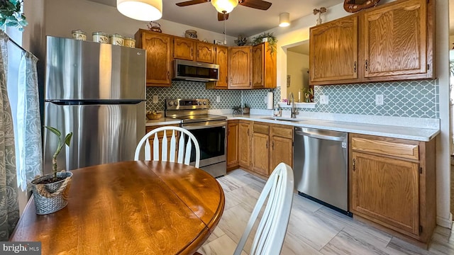 kitchen featuring stainless steel appliances, tasteful backsplash, sink, and ceiling fan