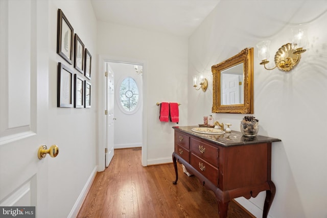 doorway to outside with a sink, baseboards, and wood finished floors