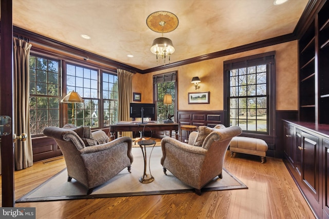 interior space featuring a wainscoted wall, light wood finished floors, a healthy amount of sunlight, and crown molding