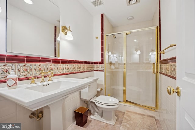 full bathroom featuring a wainscoted wall, toilet, a stall shower, and tile walls