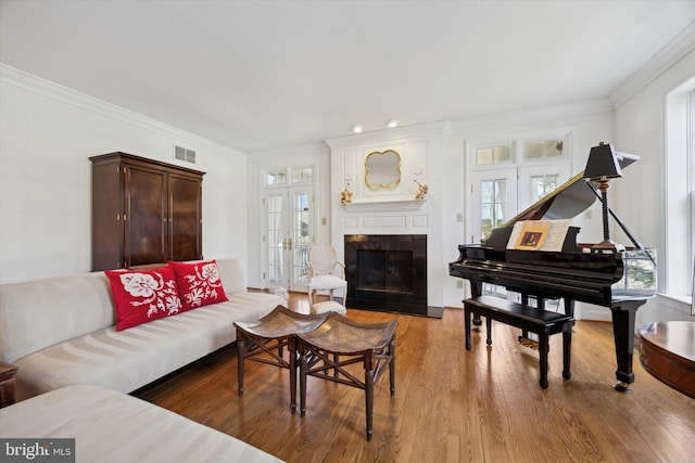 living room with a fireplace, wood finished floors, visible vents, french doors, and ornamental molding