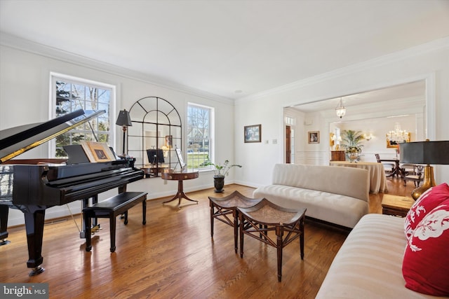 living room with an inviting chandelier, crown molding, baseboards, and wood finished floors