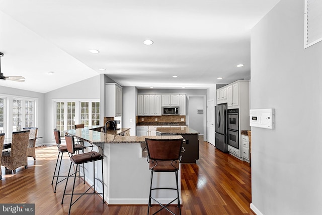 kitchen with dark stone countertops, stainless steel appliances, white cabinets, a kitchen bar, and kitchen peninsula