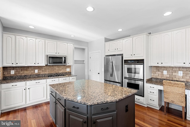 kitchen with white cabinetry, appliances with stainless steel finishes, dark hardwood / wood-style floors, and a kitchen island