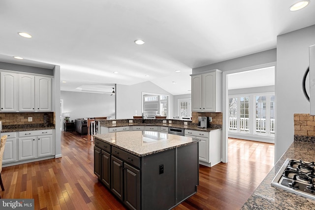 kitchen with dark stone countertops, dark hardwood / wood-style flooring, kitchen peninsula, stainless steel appliances, and white cabinets