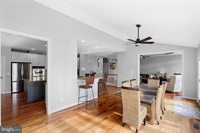 dining area featuring ceiling fan, lofted ceiling, and light hardwood / wood-style flooring