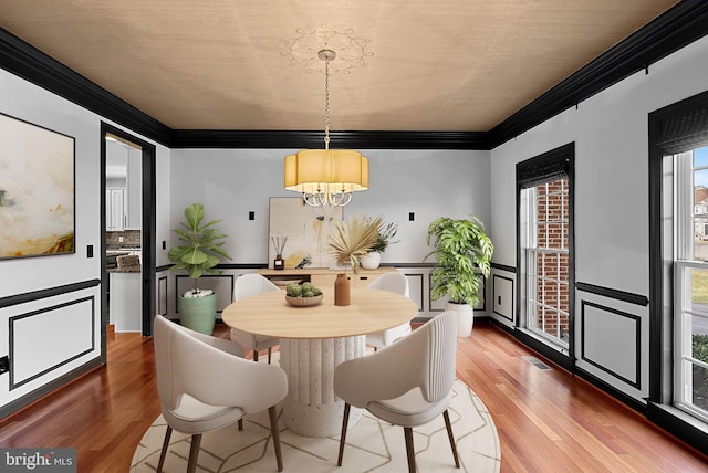 dining room with hardwood / wood-style flooring, ornamental molding, and a notable chandelier