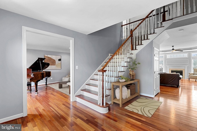 staircase with hardwood / wood-style flooring and ceiling fan