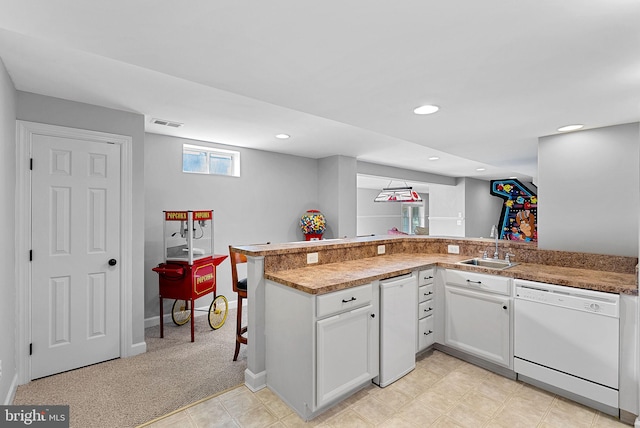 kitchen with sink, light carpet, white dishwasher, kitchen peninsula, and white cabinets