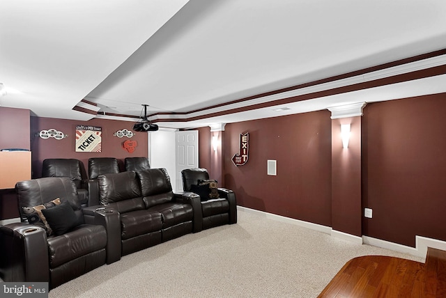 home theater room featuring a tray ceiling and ornate columns