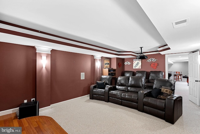 home theater room with decorative columns, a raised ceiling, and light colored carpet