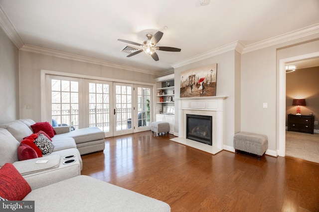 living room with dark wood-style floors, visible vents, ornamental molding, and a fireplace with flush hearth