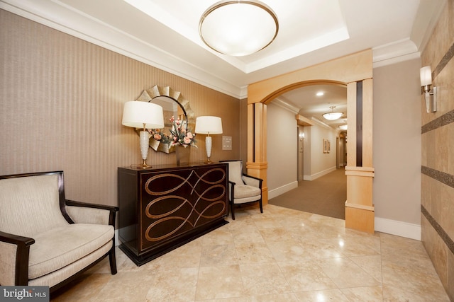 interior space featuring ornamental molding, arched walkways, a raised ceiling, and baseboards