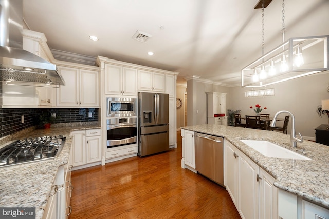 kitchen with light stone counters, visible vents, hanging light fixtures, appliances with stainless steel finishes, and a sink