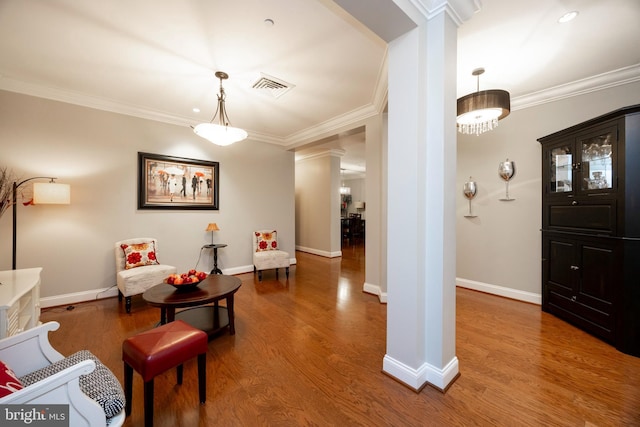 entryway featuring decorative columns, baseboards, visible vents, wood finished floors, and crown molding