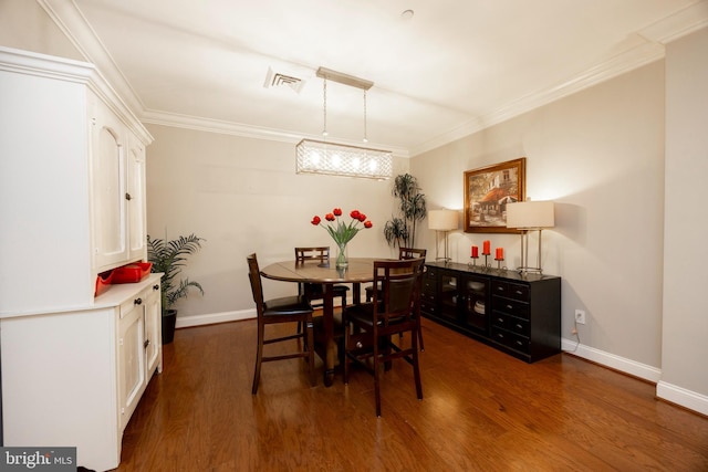 dining room with dark wood-type flooring, visible vents, and crown molding