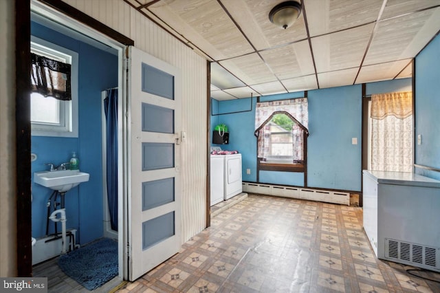 kitchen with a baseboard heating unit, sink, a wealth of natural light, and washer and dryer