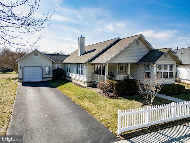 view of front of house featuring a chimney, covered porch, a front yard, fence, and driveway