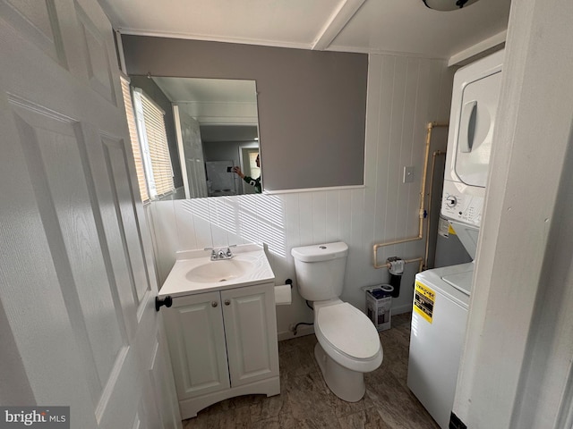 bathroom with vanity, stacked washer / drying machine, and toilet