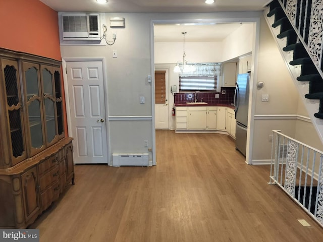 kitchen with decorative light fixtures, a baseboard radiator, stainless steel fridge, cream cabinets, and light wood-type flooring