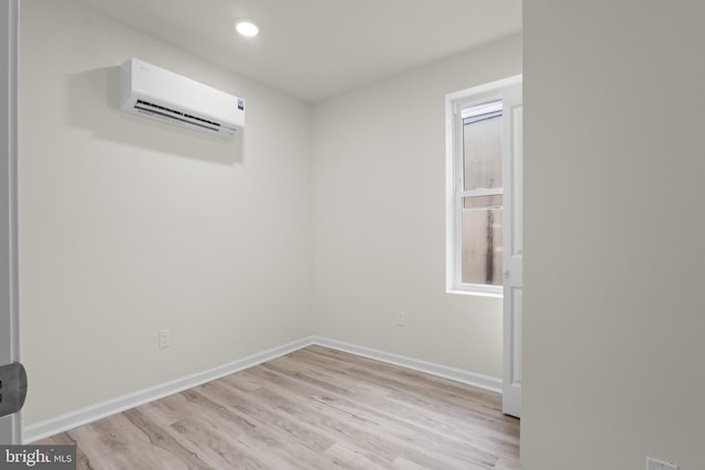 unfurnished room with an AC wall unit, light wood finished floors, recessed lighting, and baseboards