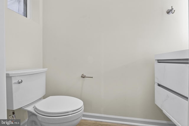 bathroom with baseboards, toilet, and wood finished floors