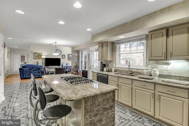 kitchen featuring sink, a center island, black dishwasher, stainless steel gas cooktop, and a kitchen bar