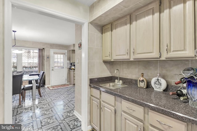 kitchen featuring tasteful backsplash, light brown cabinetry, sink, and tile walls