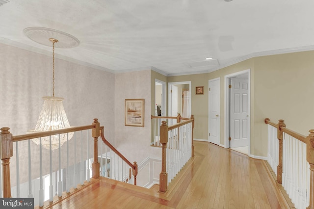 corridor featuring ornamental molding, a chandelier, and light wood-type flooring