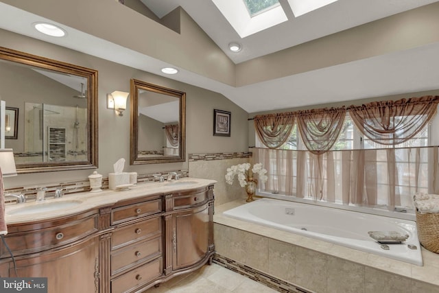 bathroom featuring vanity, lofted ceiling with skylight, tile patterned flooring, and tiled bath