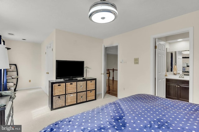 bedroom featuring connected bathroom, sink, and light carpet