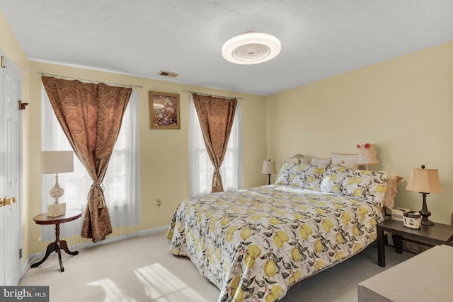 bedroom with light colored carpet and a textured ceiling