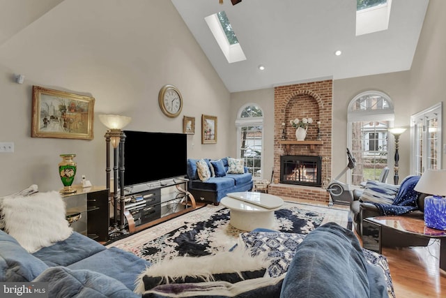 living room with high vaulted ceiling, hardwood / wood-style floors, a fireplace, and a skylight