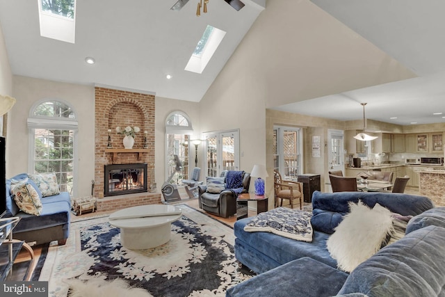 living room featuring high vaulted ceiling, a fireplace, a skylight, and hardwood / wood-style floors