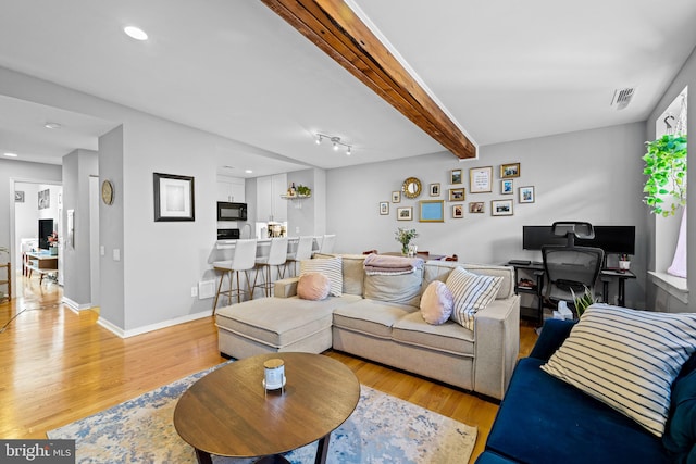 living room featuring beam ceiling and light hardwood / wood-style flooring