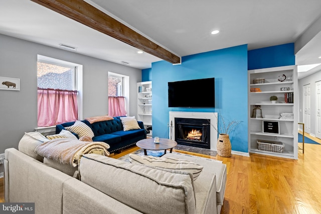 living room with beamed ceiling, built in features, and light wood-type flooring