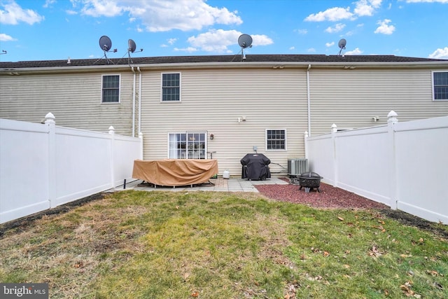 rear view of house with cooling unit, a patio area, a lawn, and an outdoor fire pit