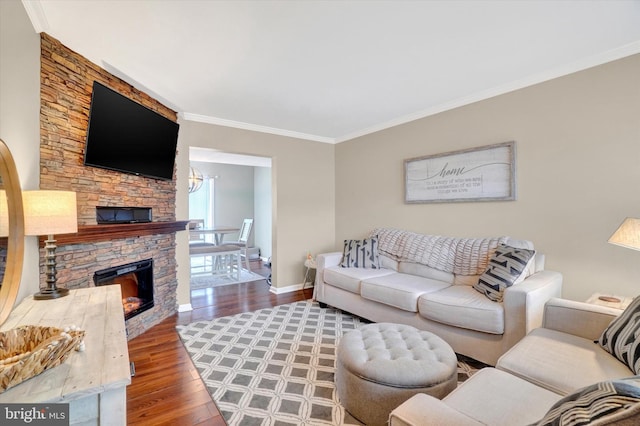 living room featuring ornamental molding, a stone fireplace, and dark wood-type flooring