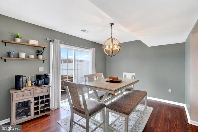 dining space with dark hardwood / wood-style floors and a chandelier